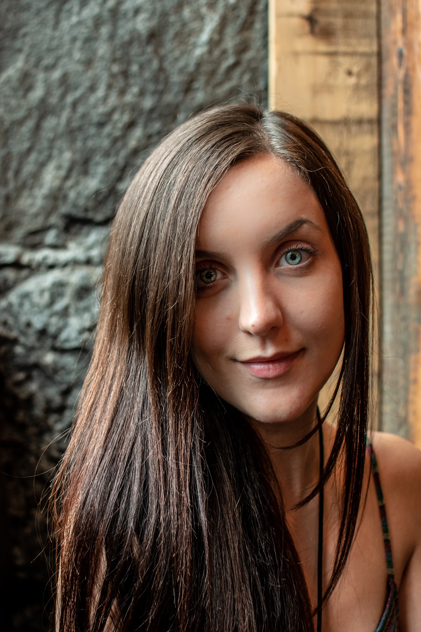 Close portrait of a woman beside a textured wall and wooden doorway