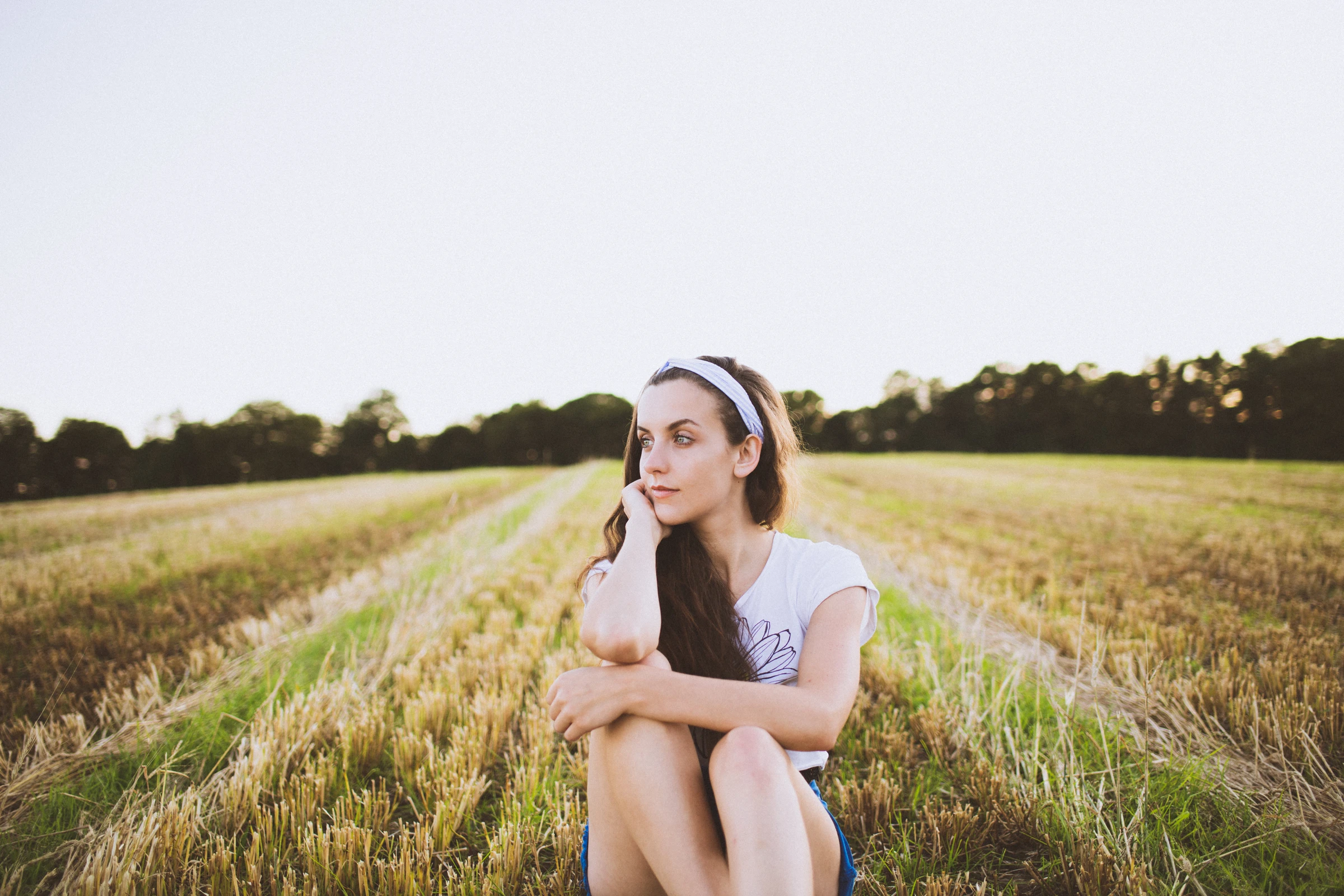 Woman seated in a harvested field in soft evening light