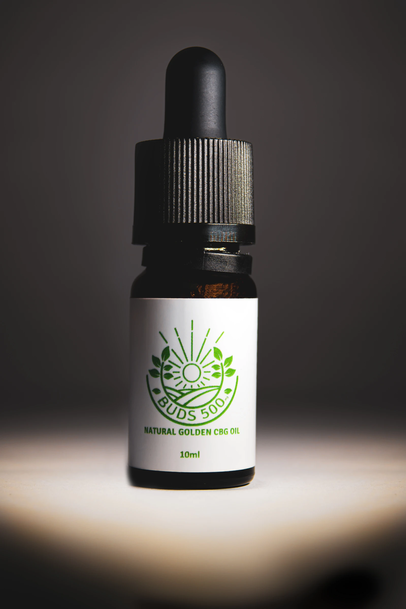 Buds oil bottle lit by a narrow pool of light