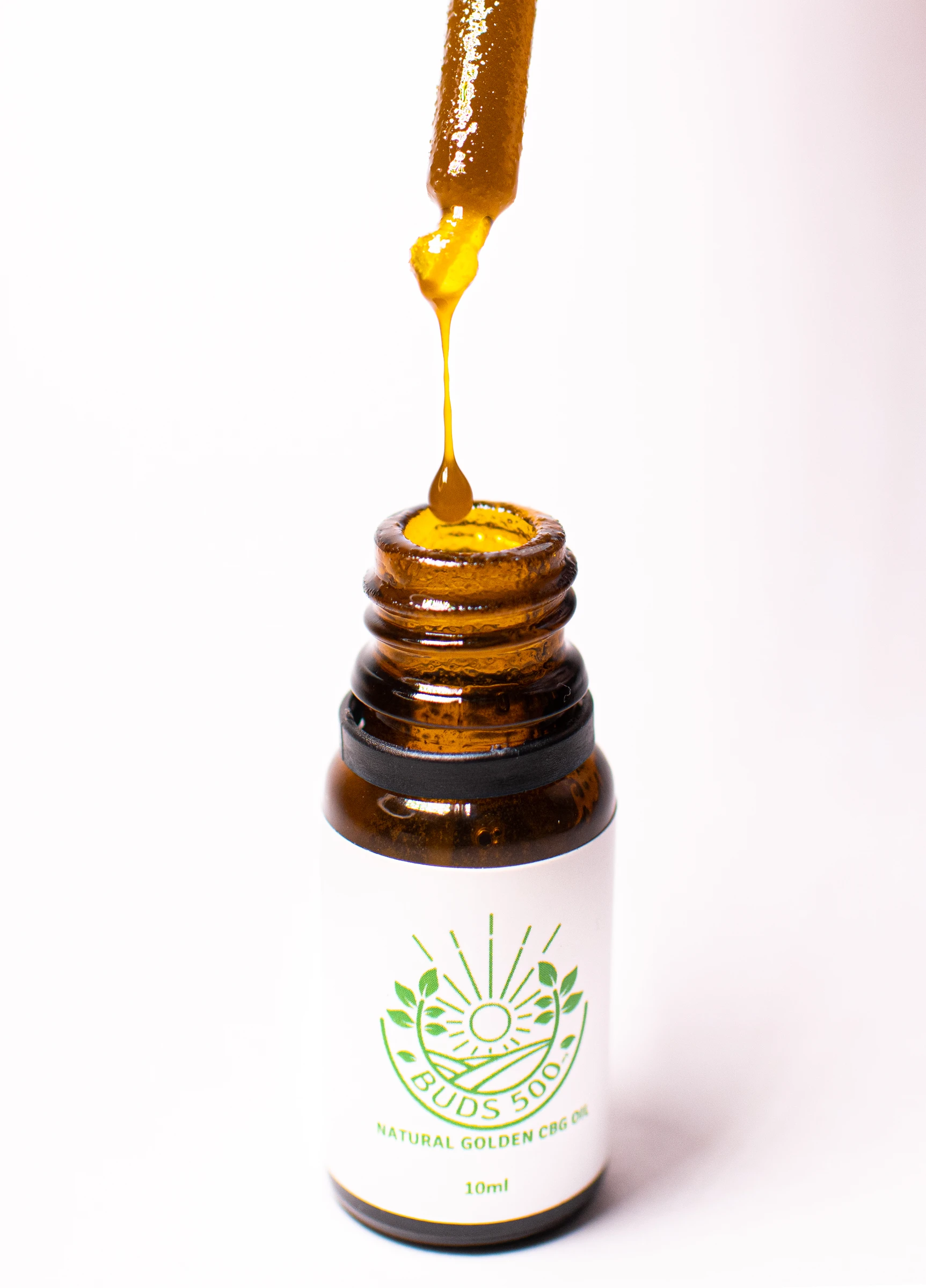 Dropper releasing a golden drop above a Buds bottle