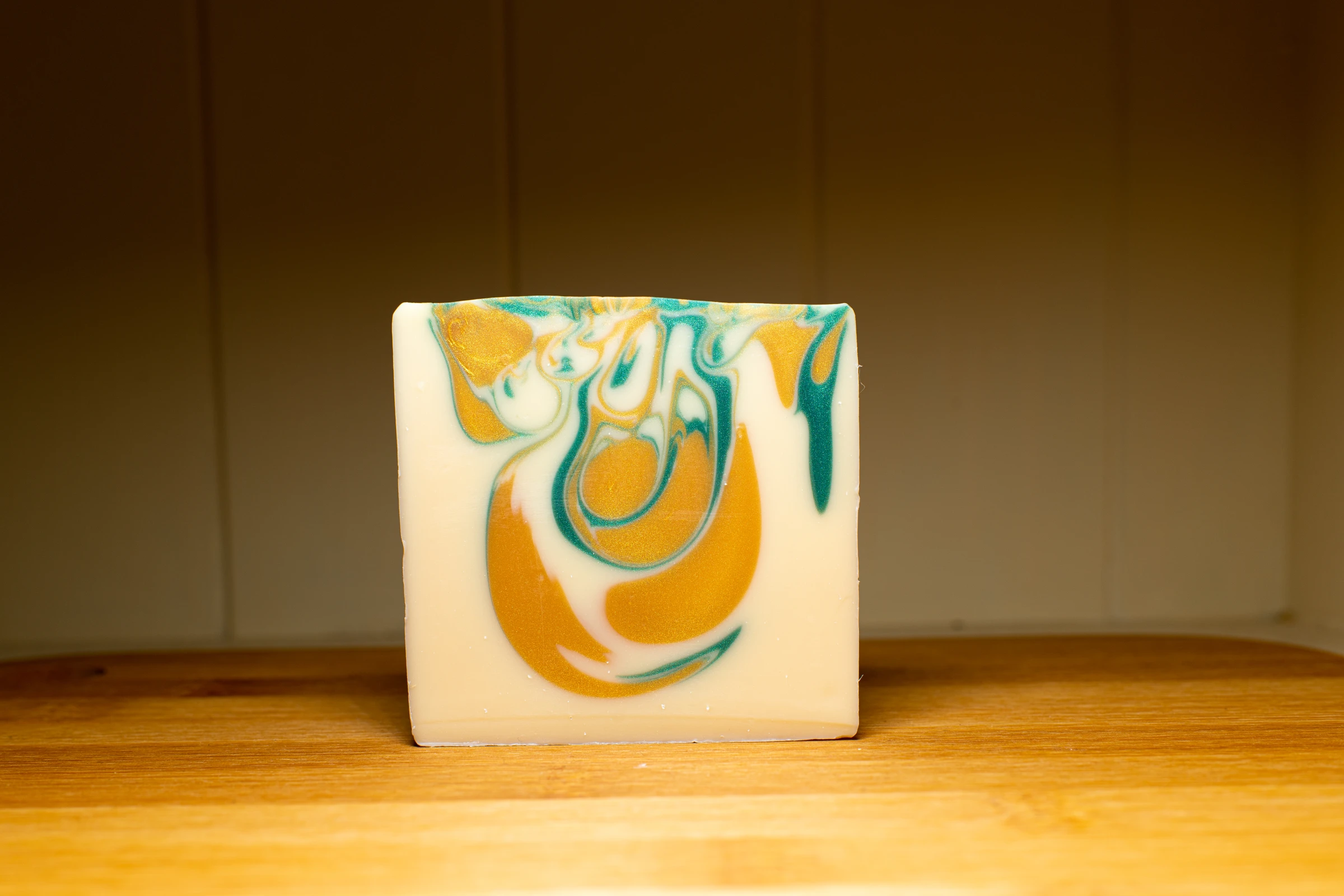 Swirled yellow and turquoise soap standing on a wooden surface