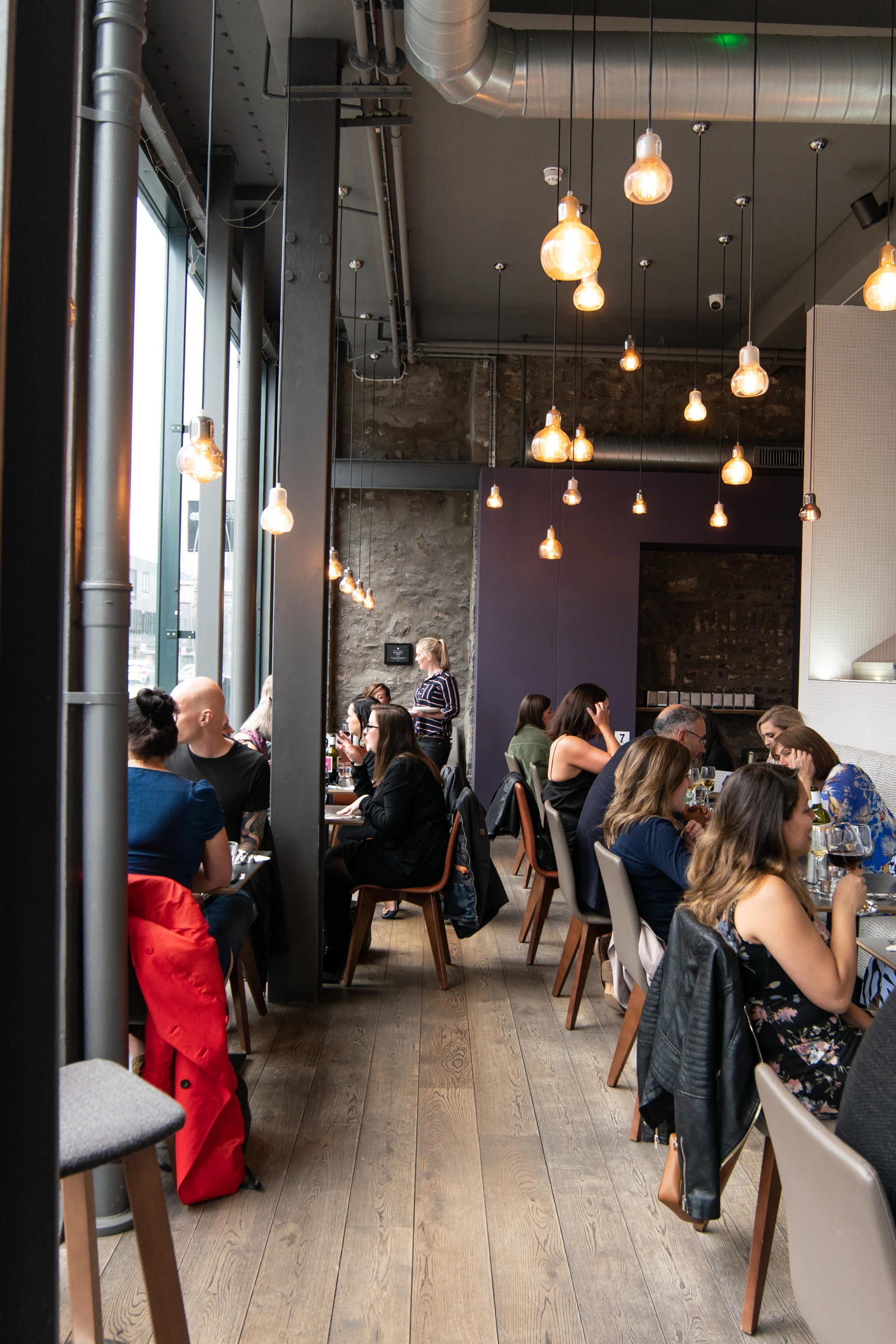 Diners seated beneath pendant lights in a restaurant